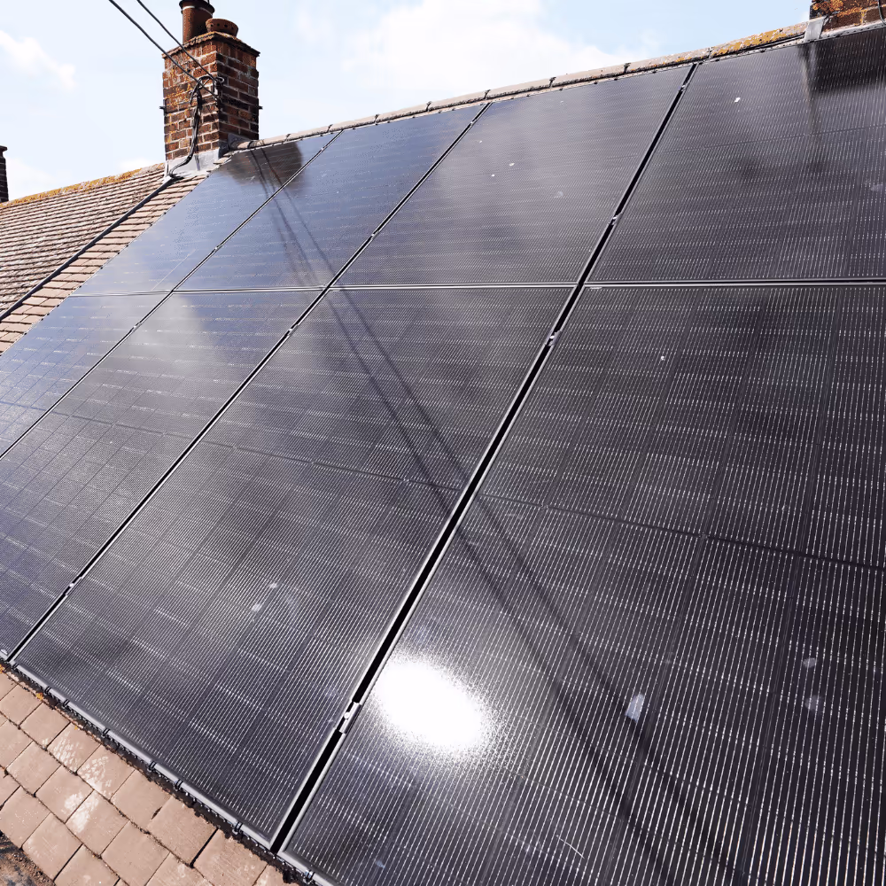 A close-up view of the black solar PV panels on the roof of a bungalow, showcasing the deep black, reflective surface and the integrated look of the energy efficiency upgrade.