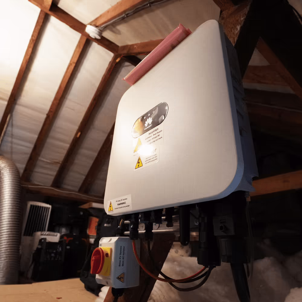 A close-up of a wall-mounted Huawei solar inverter inside a roof space, showcasing the critical component that converts solar power for household use, essential for the solar panel system.
