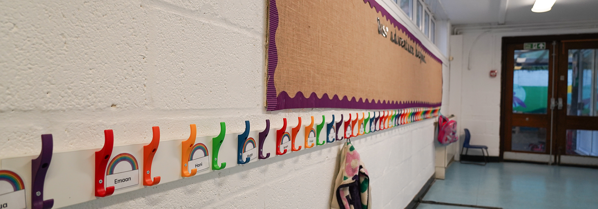 school corridor showing colour pegs and a child's coat hanging
