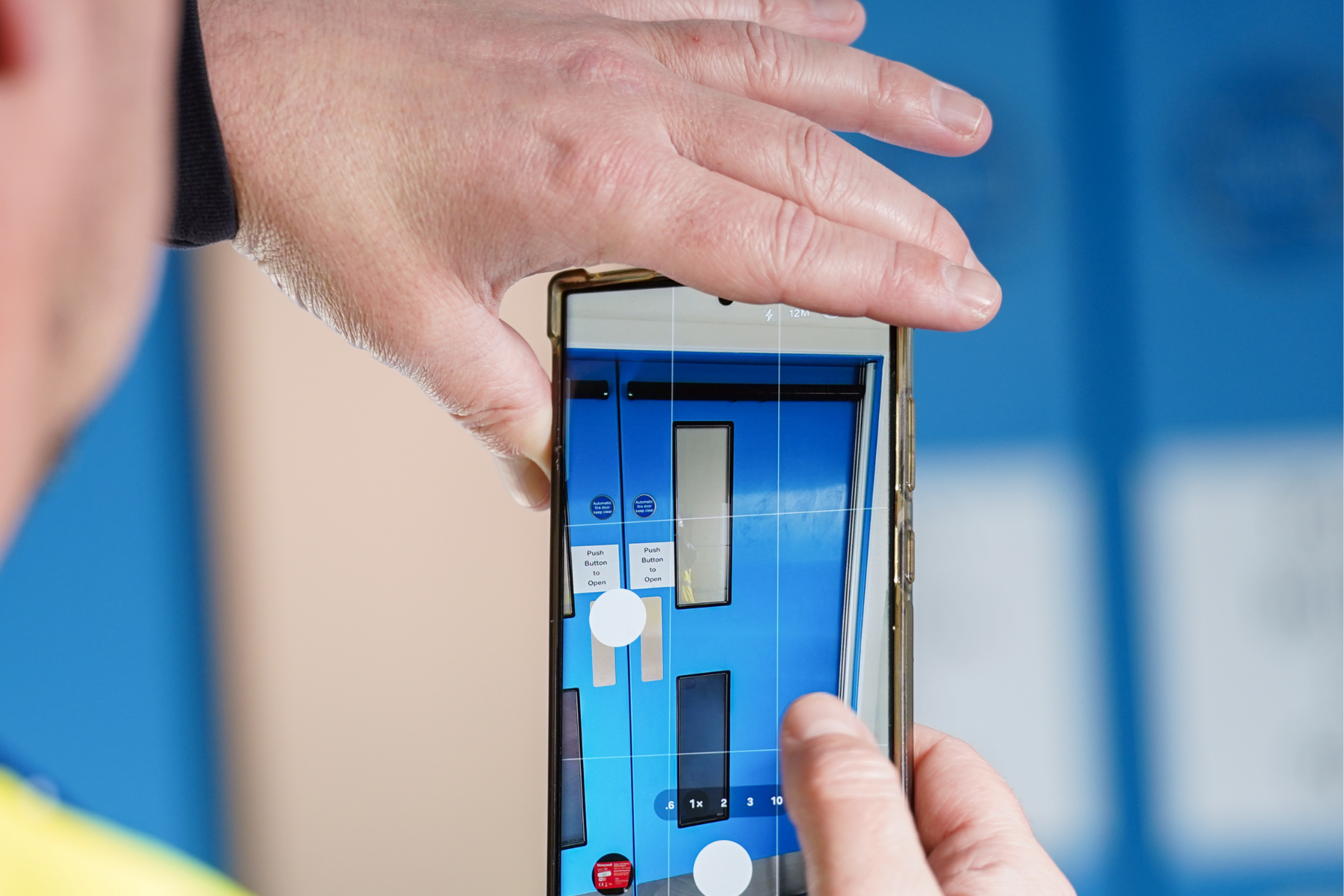 Fire door seen through phone being held by two hands