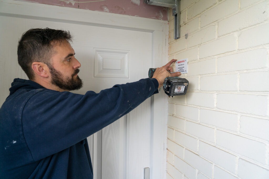 Concept staff member installing a device on an internal wall.